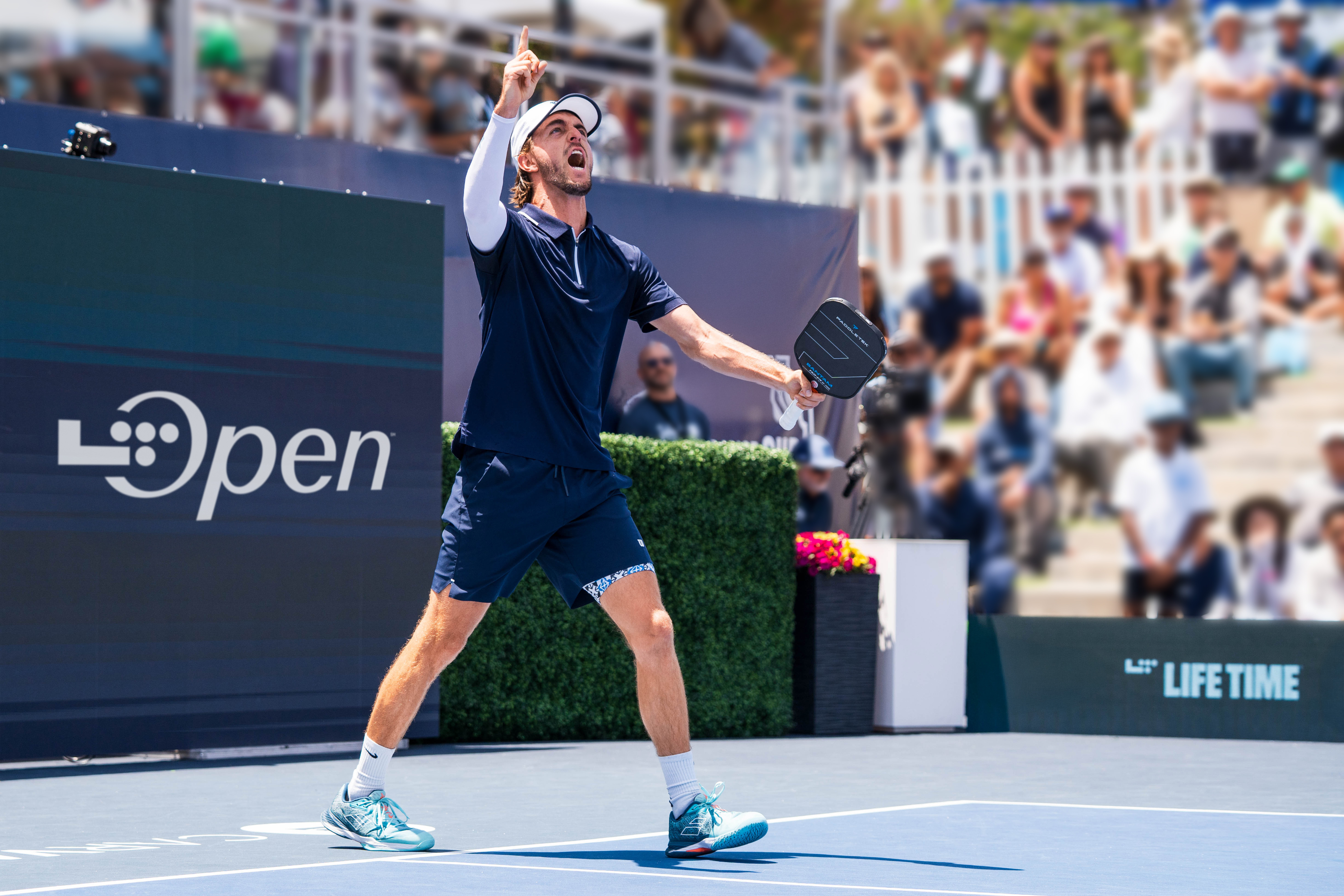 man holding his hand up in the air holding a pickleball paddle